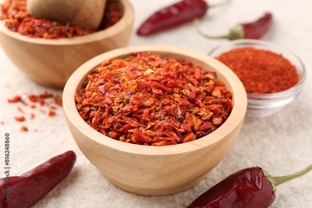 Chili pepper flakes and pods on light textured table, closeup Chili pepper flakes and pods on light textured table, closeup