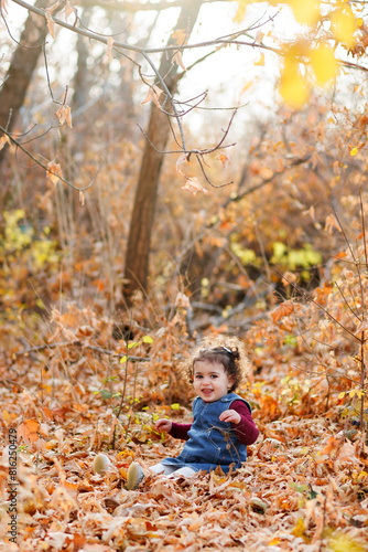Evening shot of lovely girl with blue outfit seated in a world of leaves  light  and tranquility in autumn park