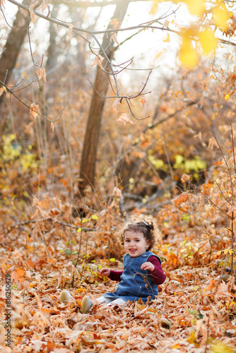Obraz na płótnie Evening shot of lovely girl with blue outfit seated in a world of leaves, light, and tranquility in autumn park w salonie