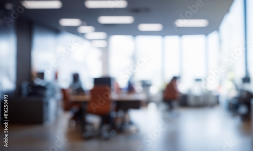 Blurred view of open space office. Abstract office interior. High windows, office furniture in the frame, tables and chairs. 