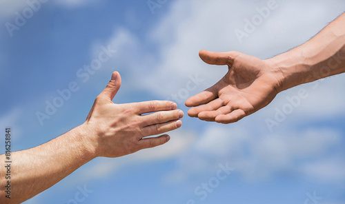 Two male hands reaching towards each other on isolated sky background. Helping hand outstretched, salvation. Close up help hand. Two hands, helping arm friend, teamwork. Helping hand