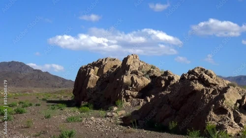 a mountain landscape, with a focus on a cluster of giant rocks set against the backdrop of majestic mountains as green bushes. a mountain landscape, with a focus on a cluster of giant rocks set against the backdrop of majestic mountains as green bushes.