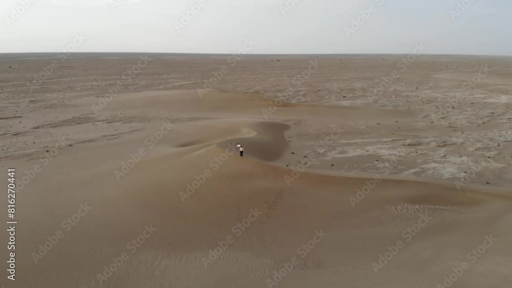 a man as he walks across the sandy desert, making his way towards a hilltop where Iran's flag is billowing in the wind. a man as he walks across the sandy desert, making his way towards a hilltop where Iran's flag is billowing in the wind.