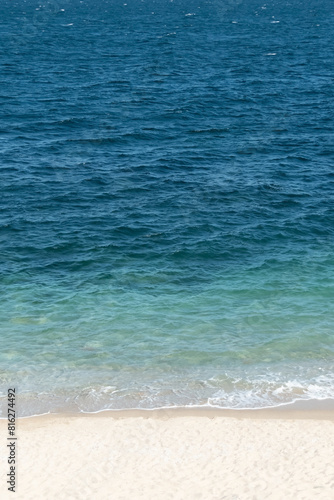 Blue and bright turquoise sea and sandy beach vertical background.