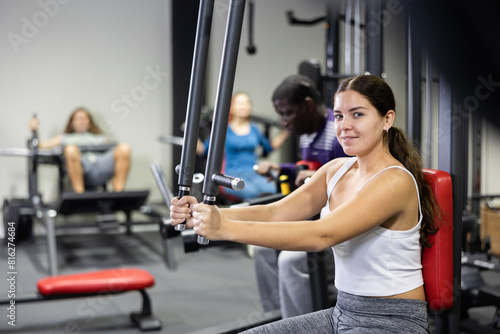 Sporty woman works on special simulator for the development of pectoral muscles