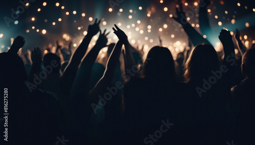 silhouettes of people having fun, hands up at a crowded party at midnight 
