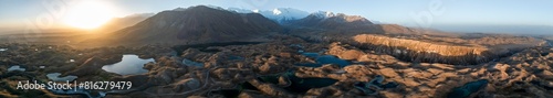 Panorama, White glaciated and snow-covered mountain peak Pik Lenin at sunrise, hilly landscape with golden meadows and lakes, aerial view, Trans Alay Mountains, Pamir Mountains, Osh Province photo