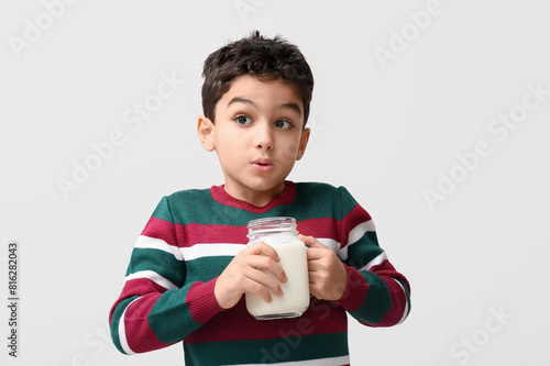 Shocked little boy with mason jar of milk on white background