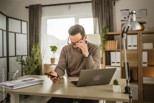 Adult man work at office on laptop and use mobile phone for message