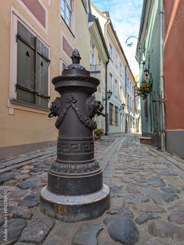 Bollard to restrict the movement of cars, decorative column on sidewalk of city street. The pole are on a on footpath in old town of Riga, Latvia.