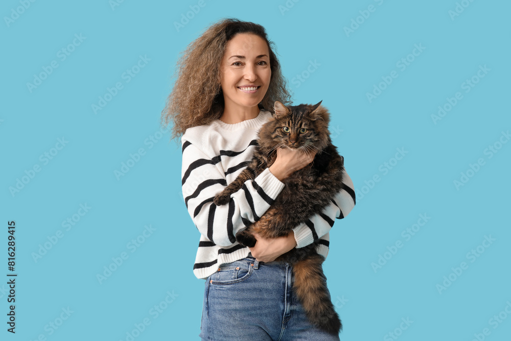 Happy mature woman with cute cat on blue background