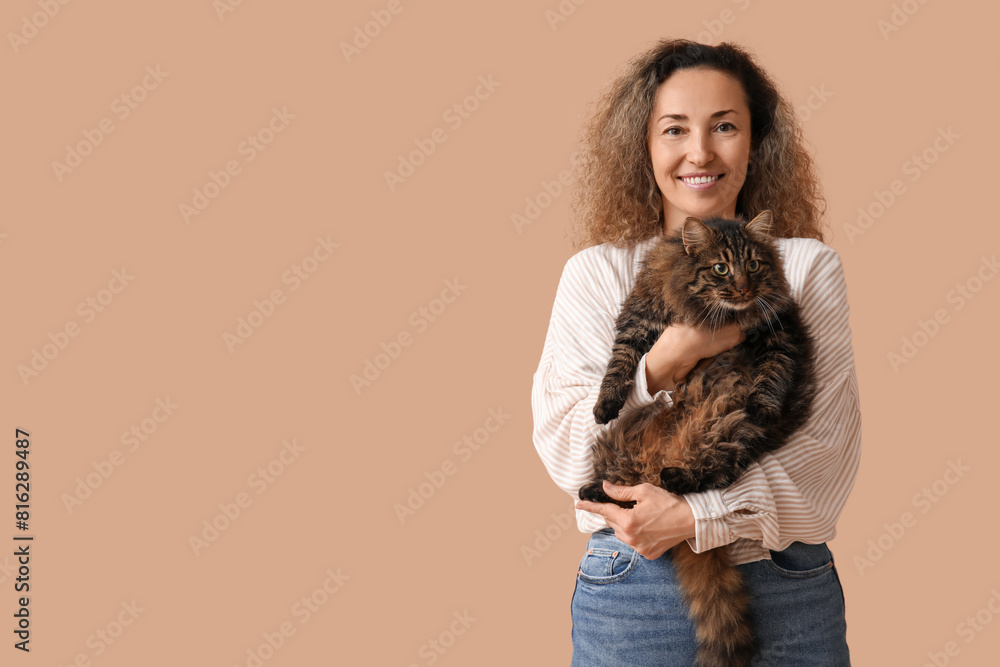 Beautiful mature woman with cute cat on brown background Beautiful mature woman with cute cat on brown background