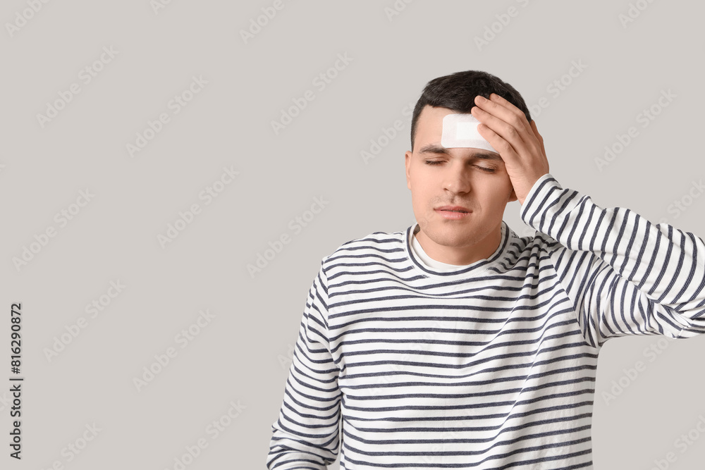 Young man with brain concussion and medical patch on light background Young man with brain concussion and medical patch on light background