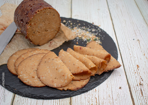 Seitan shaped and cooked in ham press, sliced on slate board. Vegan protein, plant based alternative to meat.