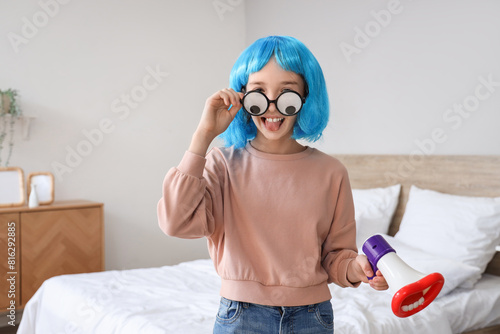 Funny little girl in disguise with megaphone at home. April Fools' Day celebr...