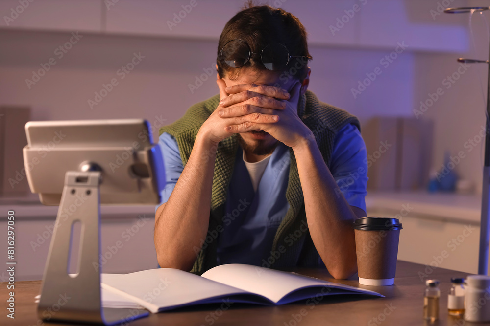 Tired male nurse studying at hospital in evening Tired male nurse studying at hospital in evening