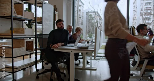 Wallpaper Mural In a modern office setting, a young woman discusses a document with a seated male colleague surrounded by other focused coworkers. Torontodigital.ca