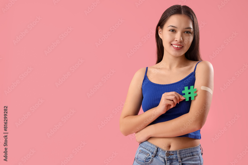 Beautiful young woman with applied medical patch holding hashtag sign on pink background Beautiful young woman with applied medical patch holding hashtag sign on pink background