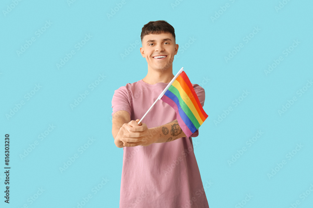 Handsome young happy man with LGBT flag on blue background Handsome young happy man with LGBT flag on blue background