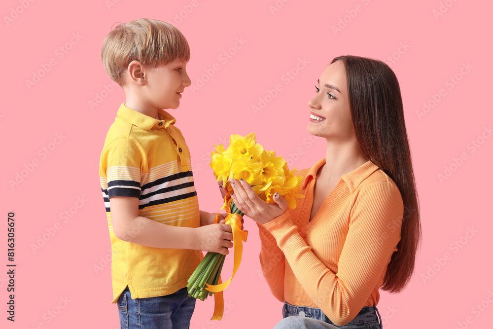 Son greeting his happy mother with bouquet of beautiful narcissus on pink background Son greeting his happy mother with bouquet of beautiful narcissus on pink background