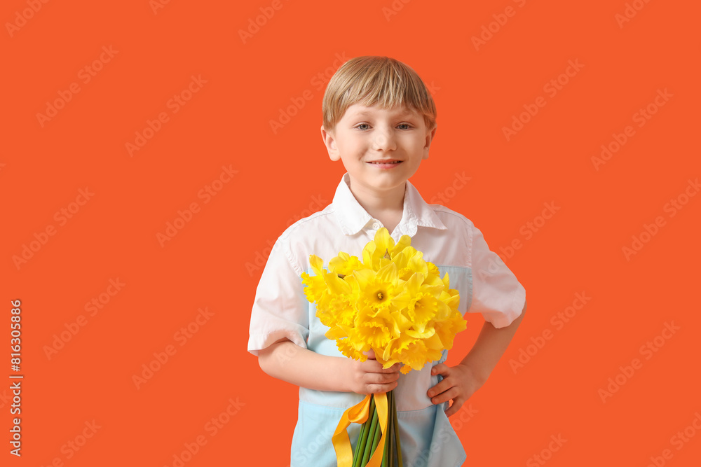 Cute little happy boy with bouquet of beautiful narcissus on orange background Cute little happy boy with bouquet of beautiful narcissus on orange background