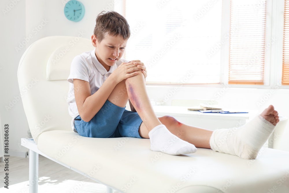 Little boy with injured leg sitting on couch in clinic Little boy with injured leg sitting on couch in clinic