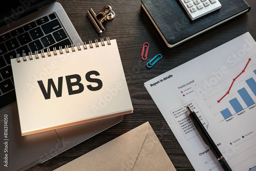 There is notebook with the word WBS. It is an abbreviation for Work Breakdown Structure as eye-catching image.