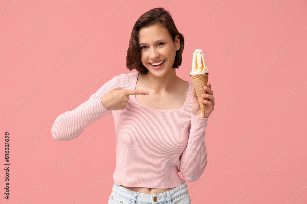 Beautiful young woman pointing at sweet ice-cream in waffle cone on pink background Beautiful young woman pointing at sweet ice-cream in waffle cone on pink background