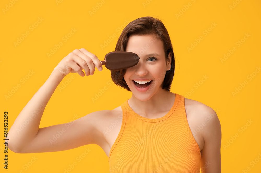 Beautiful young woman with chocolate covered sweet ice-cream on yellow background Beautiful young woman with chocolate covered sweet ice-cream on yellow background