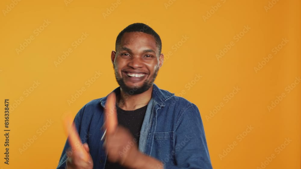 Cheerful guy mimics playing drums with two carrots in studio, having fun with ethically sourced organic produce. Happy silly person fooling around with ripe fresh veggies. Camera A. Cheerful guy mimics playing drums with two carrots in studio, having fun with ethically sourced organic produce. Happy silly person fooling around with ripe fresh veggies. Camera A.