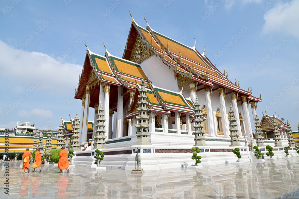 BANGKOK, THAILAND - May 17, 2024: Monks walking in front of Wat Suthat Thepwararam Ratchaworamahawihan with blue sky background, Phra Nakhon, Bangkok, Thailand.