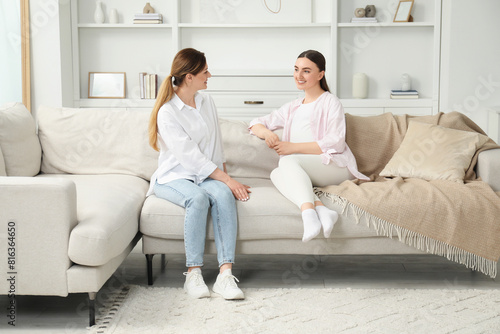 Doula working with pregnant woman on sofa at home. Preparation for child birth