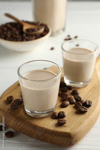 Coffee cream liqueur in glasses and beans on white wooden table