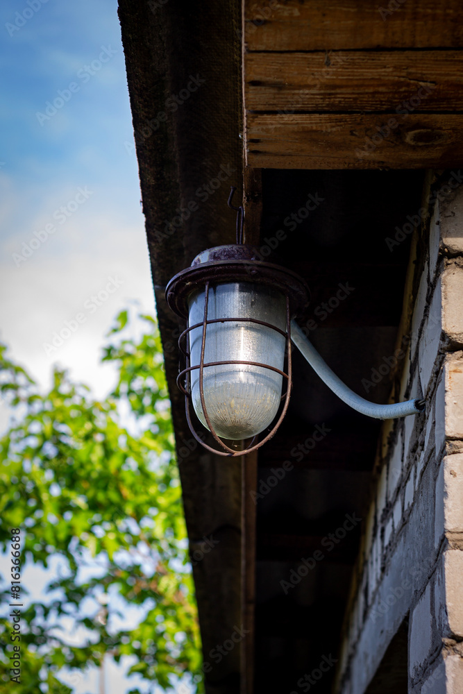 Fototapeta premium An old lantern with cloudy glass is fixed on the roof of a brick shed