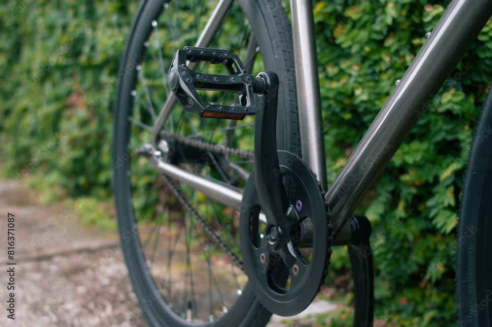 black crankset of fixed-gear bicycle on blurred grass background black crankset of fixed-gear bicycle on blurred grass background