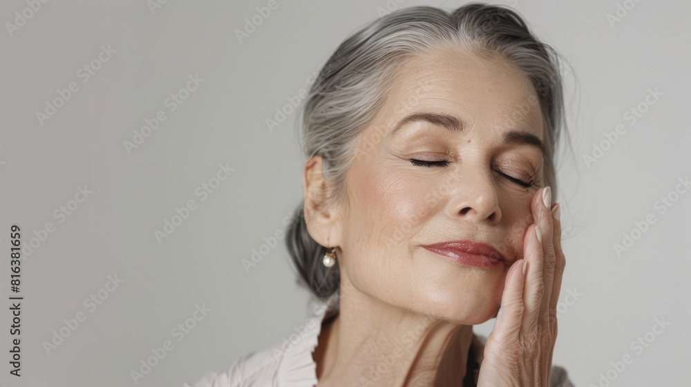 Elegant middle-aged woman with closed eyes gently touching her smooth skin on white background Elegant middle-aged woman with closed eyes gently touching her smooth skin on white background