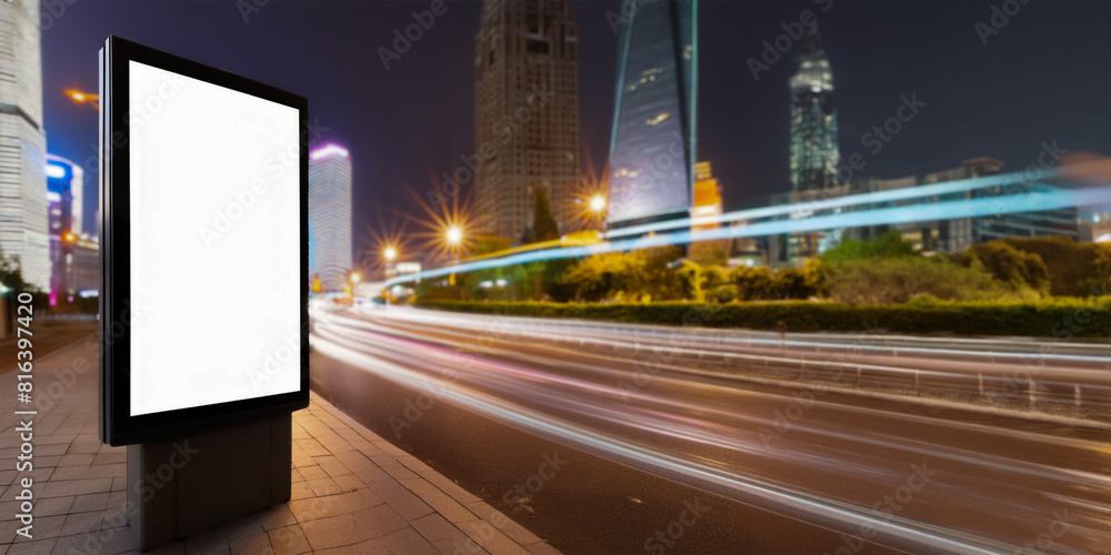 Mockup, blank, illuminated advertising hoarding in city street at night. Tall skyscrapers and motion blur from moving traffic. Mockup, blank, illuminated advertising hoarding in city street at night. Tall skyscrapers and motion blur from moving traffic.
