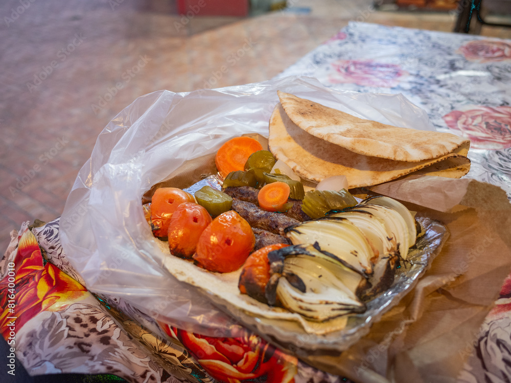 a box of kebab, tomato, and onions on the table of the restaurant in amman a box of kebab, tomato, and onions on the table of the restaurant in amman