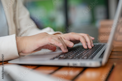 A close-up image of a woman using her laptop computer, typing on the laptop keyboard.