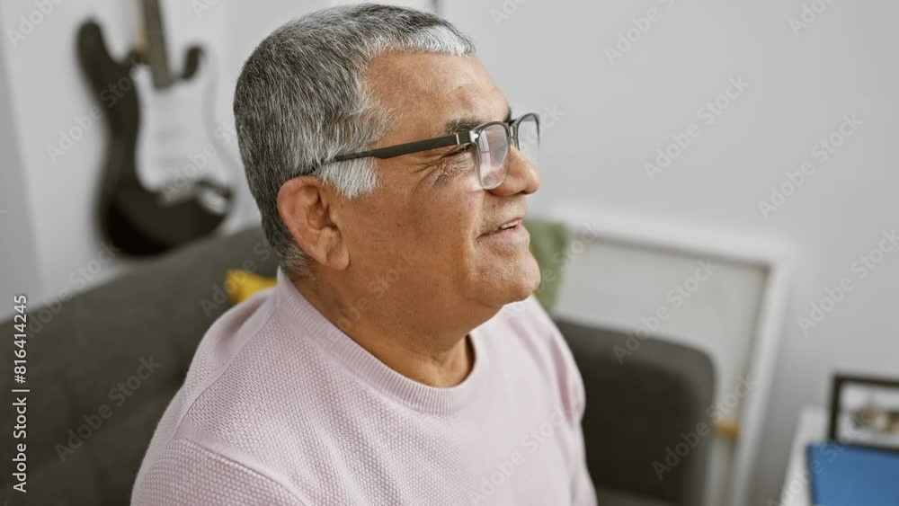 Gray-haired senior man with glasses smiling warmly in a cozy living room Gray-haired senior man with glasses smiling warmly in a cozy living room