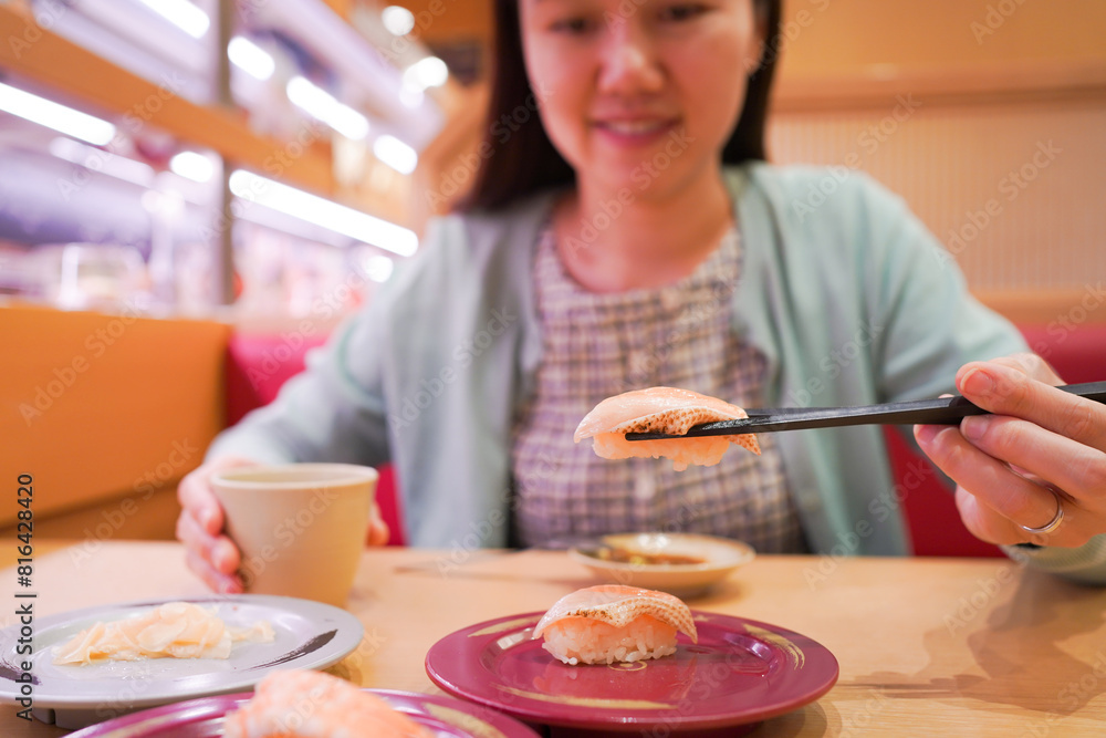 Happy Asian woman eating Sushi at modern Japanese Sushi bar. Happy Asian woman eating Sushi at modern Japanese Sushi bar.