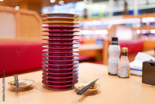 Close up shot of stacked Sushi plates on the dining table in conveyor belt Sushi bar.
