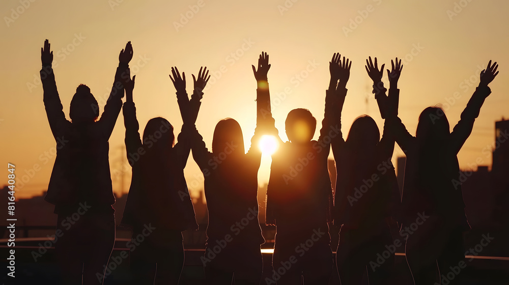 Fototapeta premium Silhouettes of anonymous group of friends standing together with raised arms near border on street at sunset time in city : Generative AI