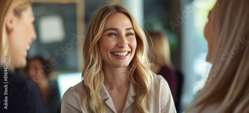 Portrait of a smiling blonde business woman in an office talking to other women during a meeting. Close-up, high-detail, ultra-realistic photo shot using a