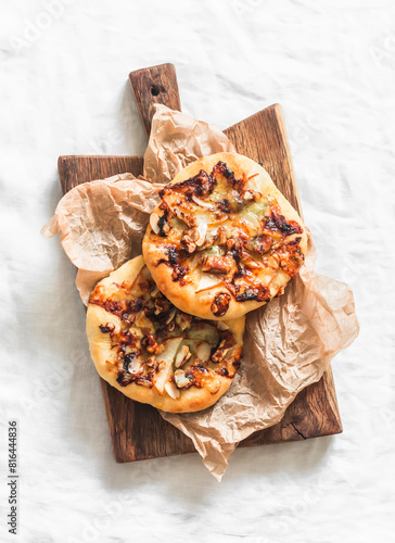 Vegetarian menu pizza with caramelized pearl, blue cheese, honey and walnuts on a wood chopping board on a light background, top view