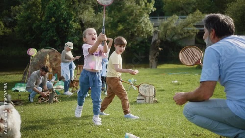 Grandfather and granddaughter play bagminton on camping in nature with family photo