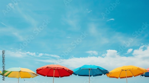 Six colorful beach umbrellas are arranged in a row against a blue sky with white clouds. The umbrellas are red  blue  green yellow and orange.