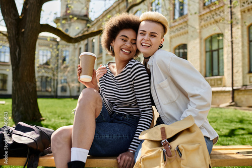 Two young girls with stylish attire sit on a bench, sipping coffee in a serene moment outdoors.