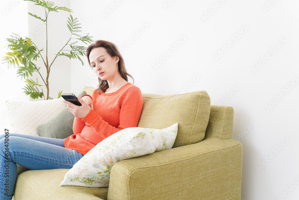 Obraz premium 家でスマホを使う若い女性