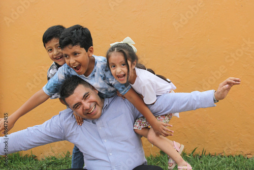 Divorced single dad has fun with his three dark-skinned Latino kids spending quality time and celebrating Father's Day